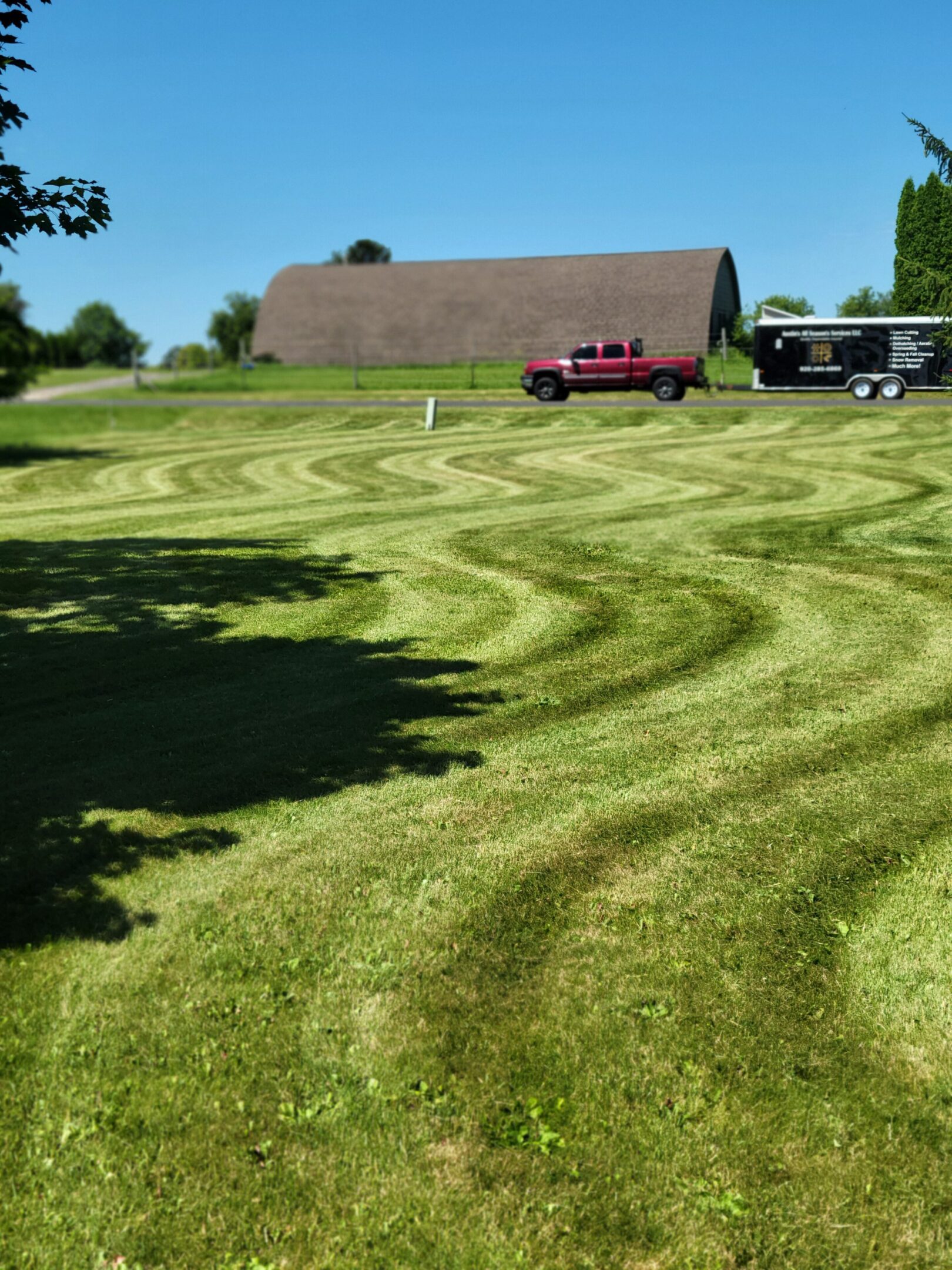 Freshly mowed lawn with swirling patterns and two parked vehicles.