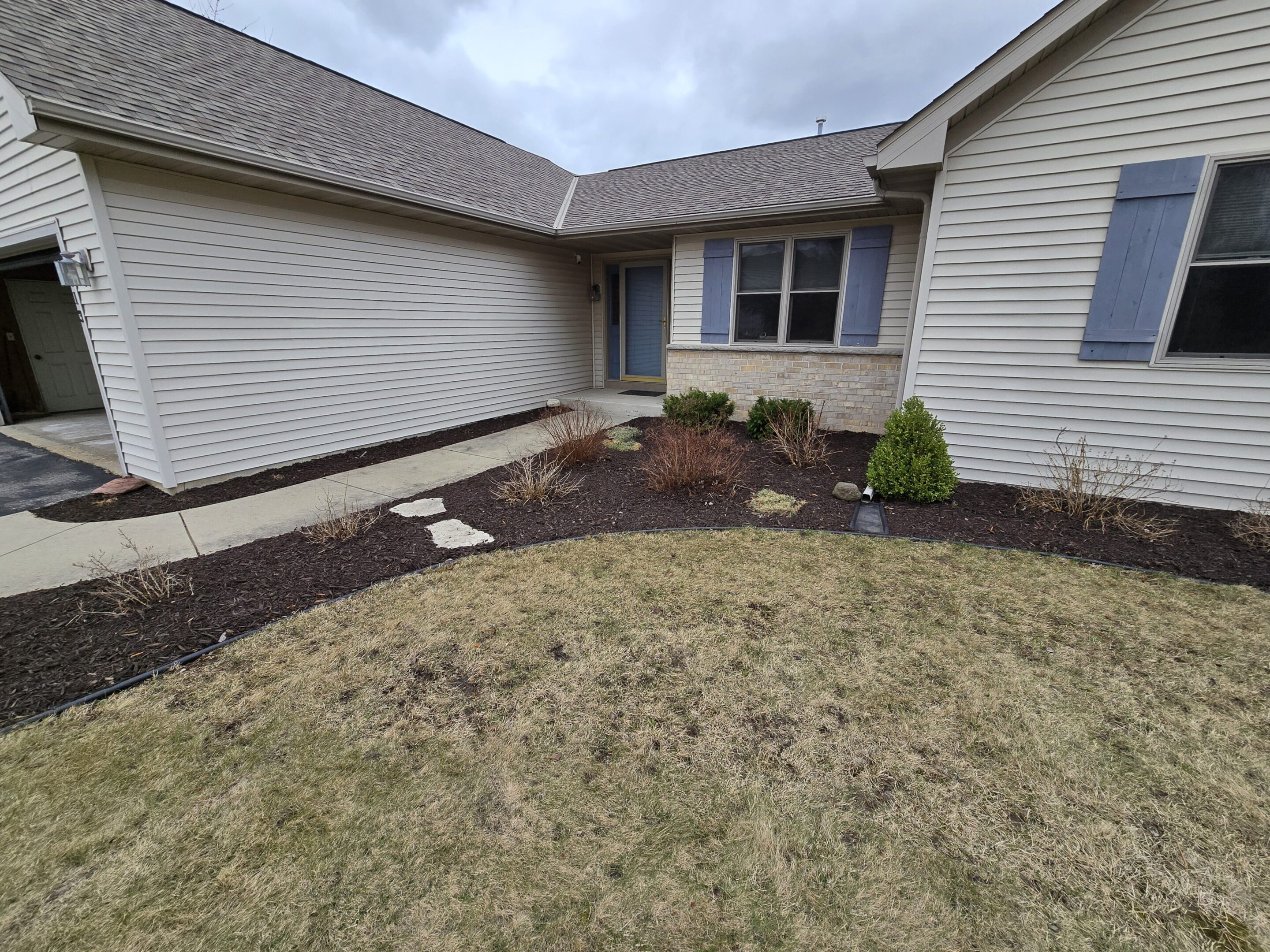 A tidy front yard with newly mulched flower beds and a stone pathway.