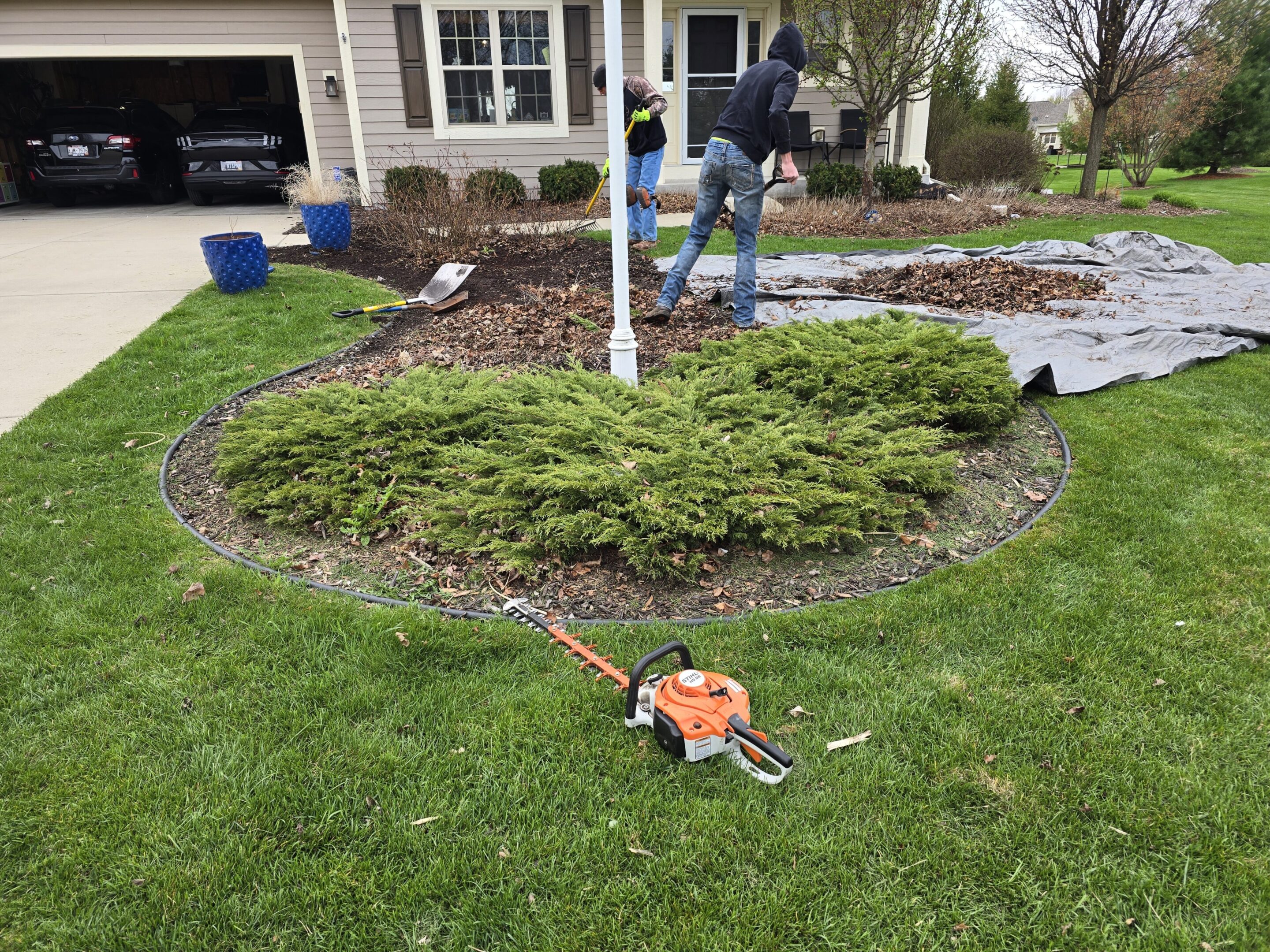 Person gardening with tools in a suburban yard.