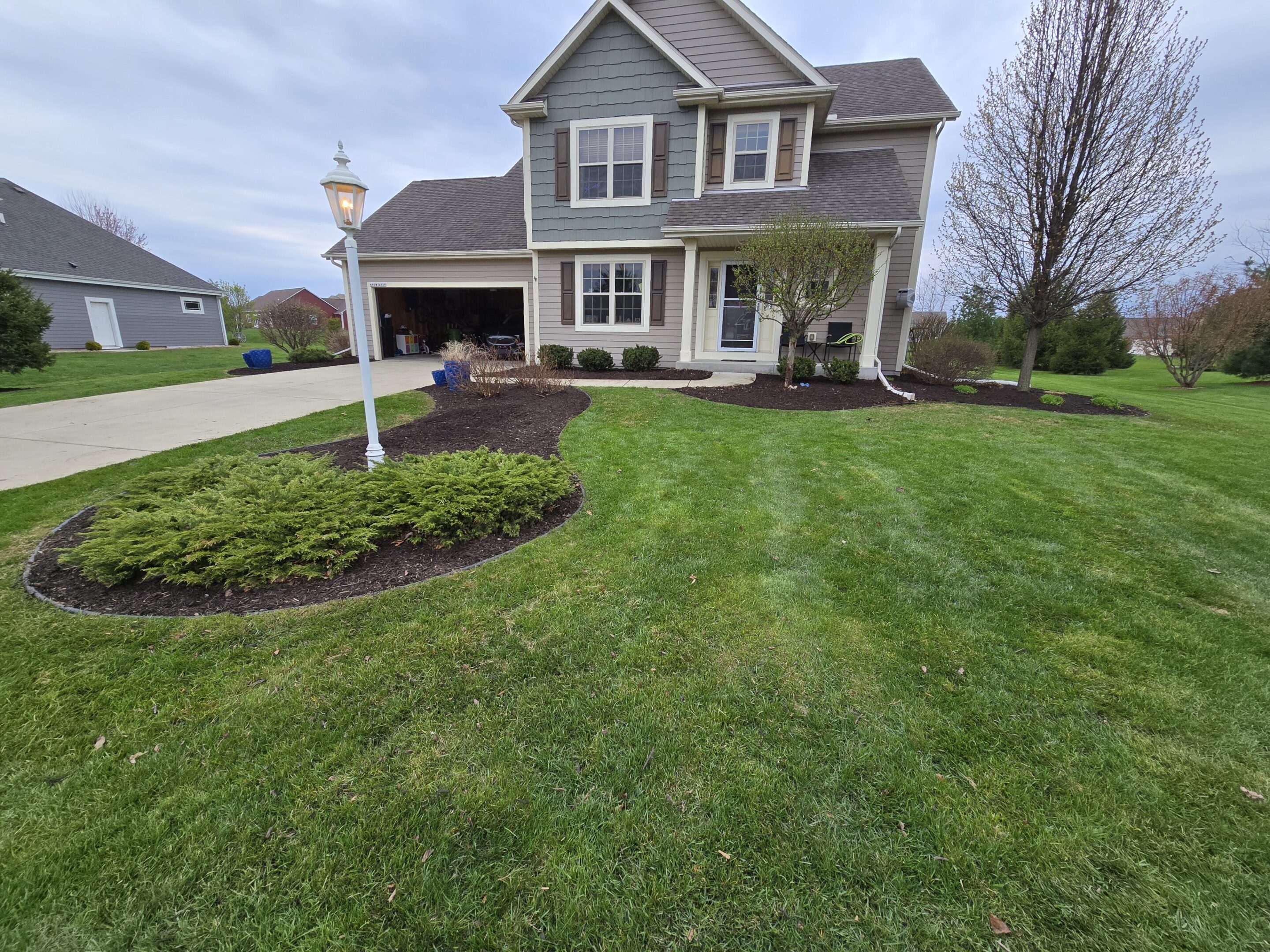 Well-maintained suburban house with manicured lawn and garden beds.