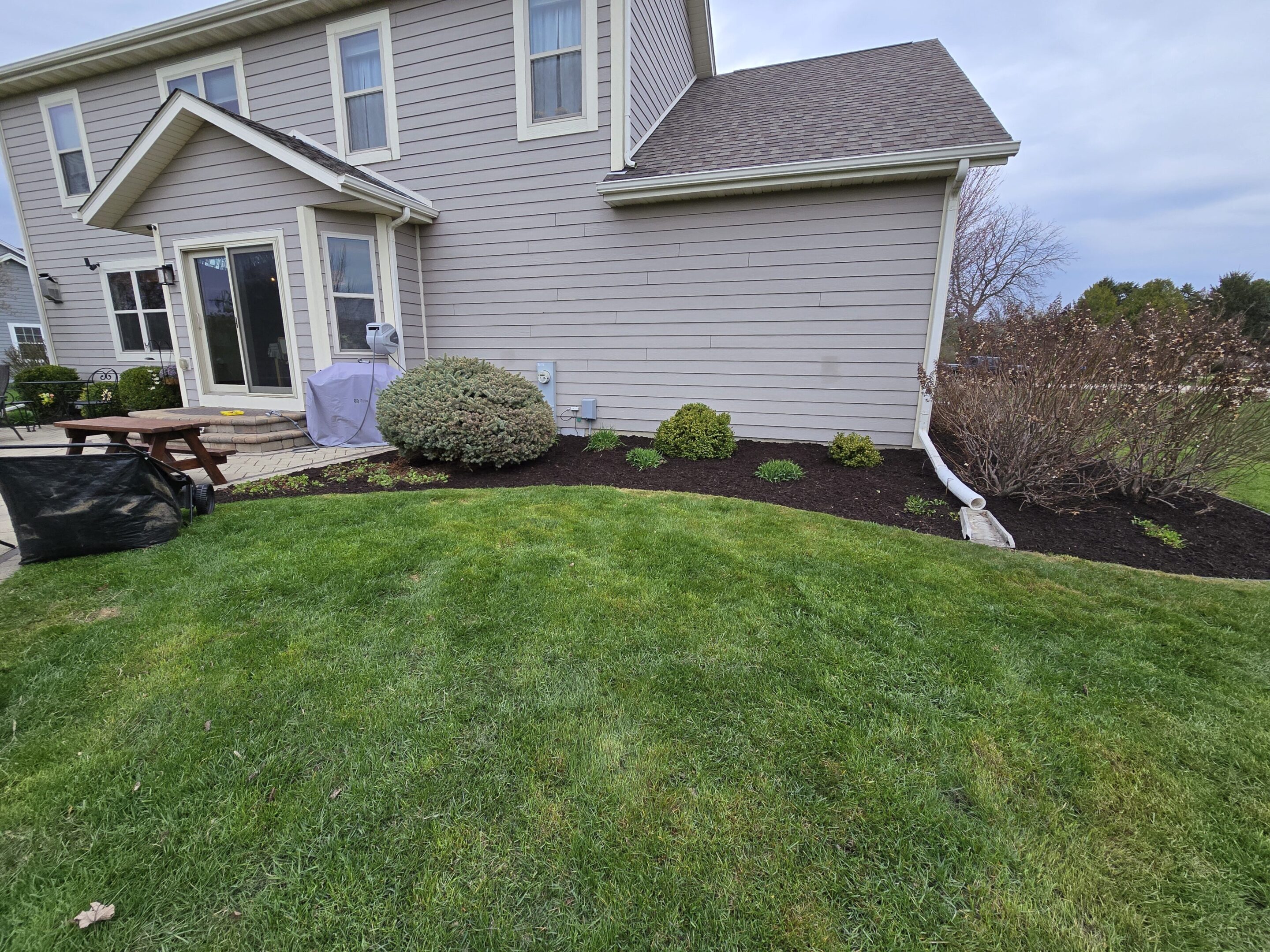 Well-maintained lawn and garden bed near a house corner.
