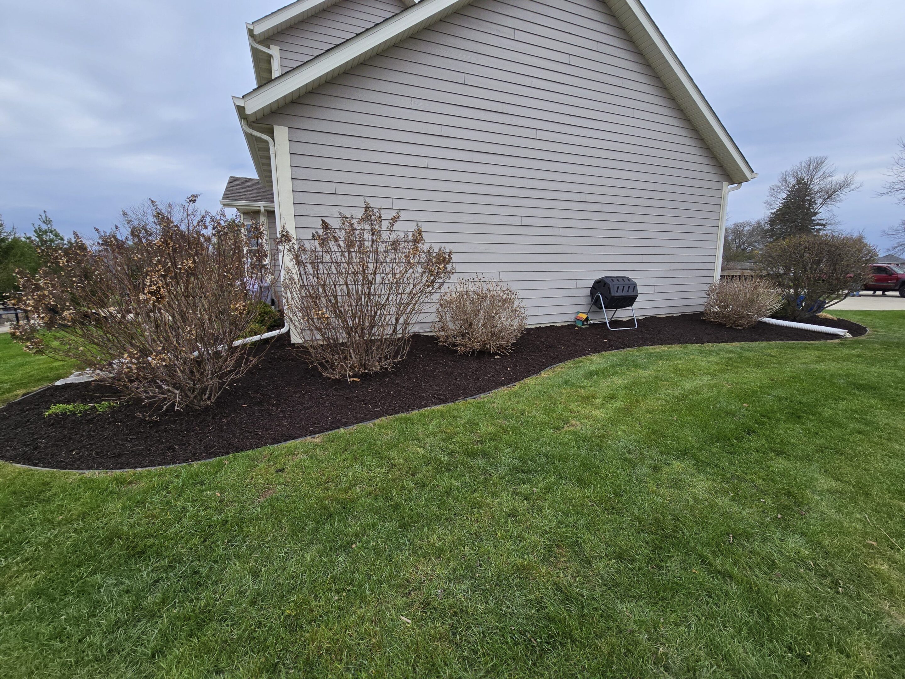 Well-maintained garden bed with fresh mulch beside a house's exterior wall.