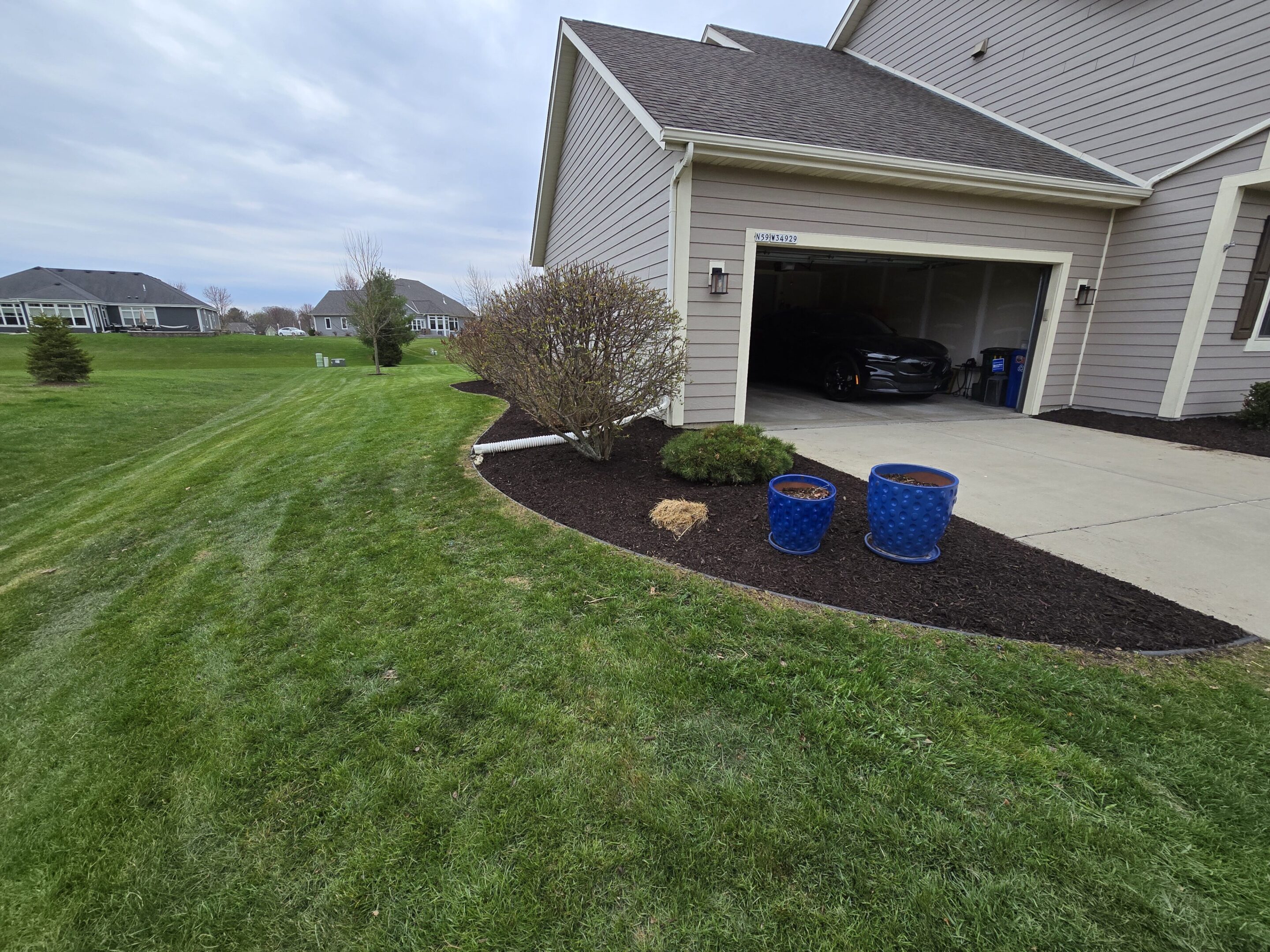 Neatly landscaped yard with fresh mulch and planted flowers near a garage.