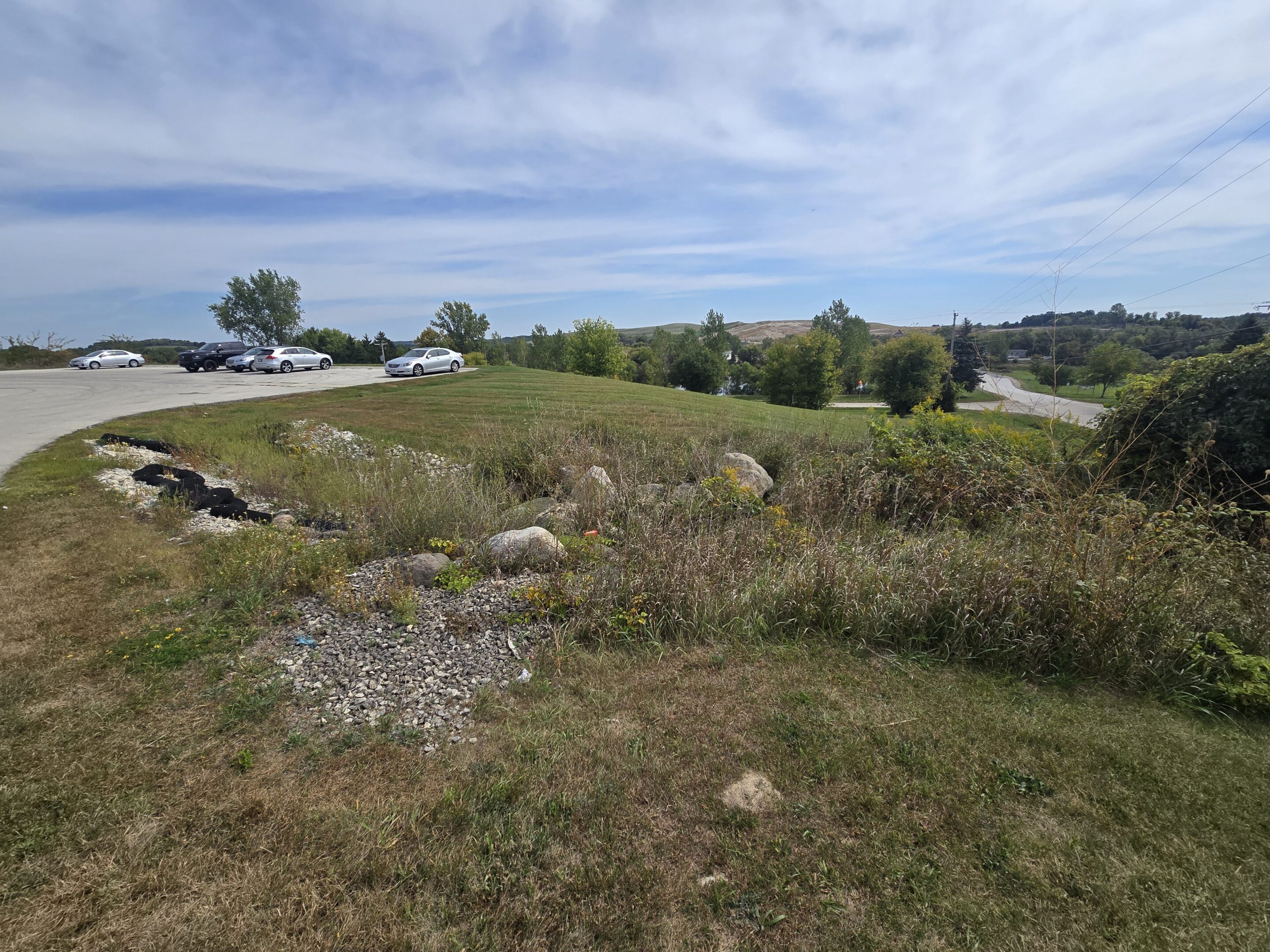 Open grassy area with scattered rocks under a partly cloudy sky.