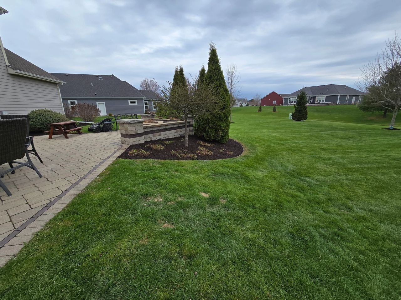 A well-maintained lawn with trees and houses in the background.